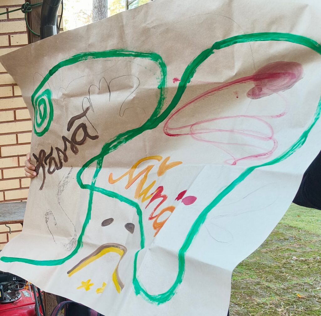 Olemisen riemu hankkeessa tehty taideterapeuttinen maalaus. Kuvassa menee vihreä nauha ja siinä on hymiö, joka on tulkittavissa molemmin päin.